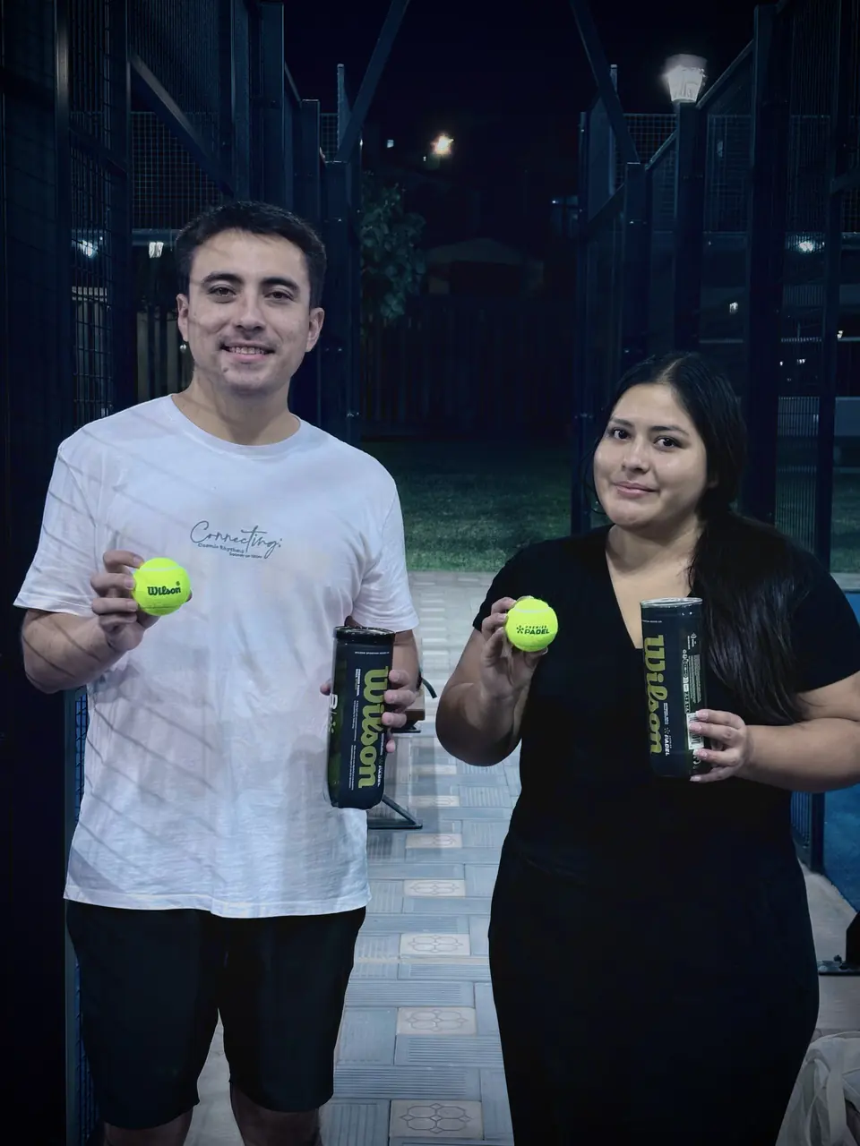 Dos jugadores mostrando pelotas de pádel Wilson