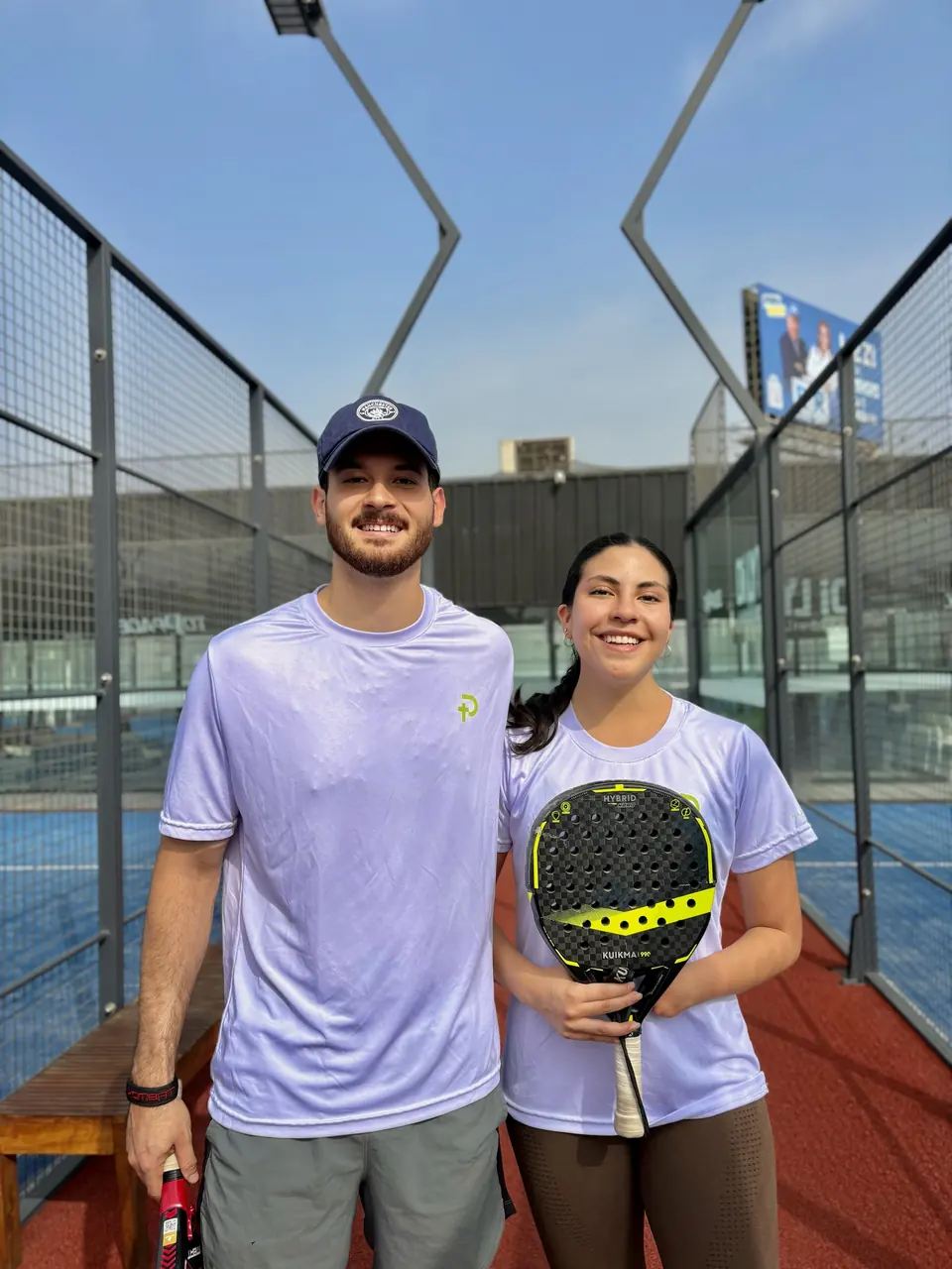 Pareja de jugadores con polos Padelhood sonriendo en la cancha