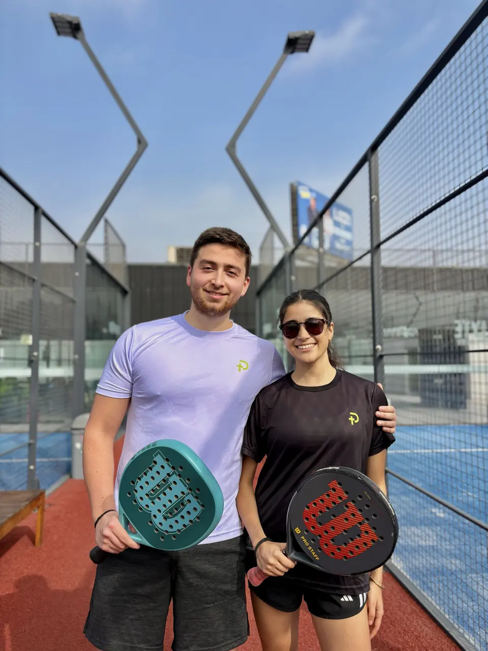 Pareja de jugadores mostrando sus raquetas Wilson en la cancha
