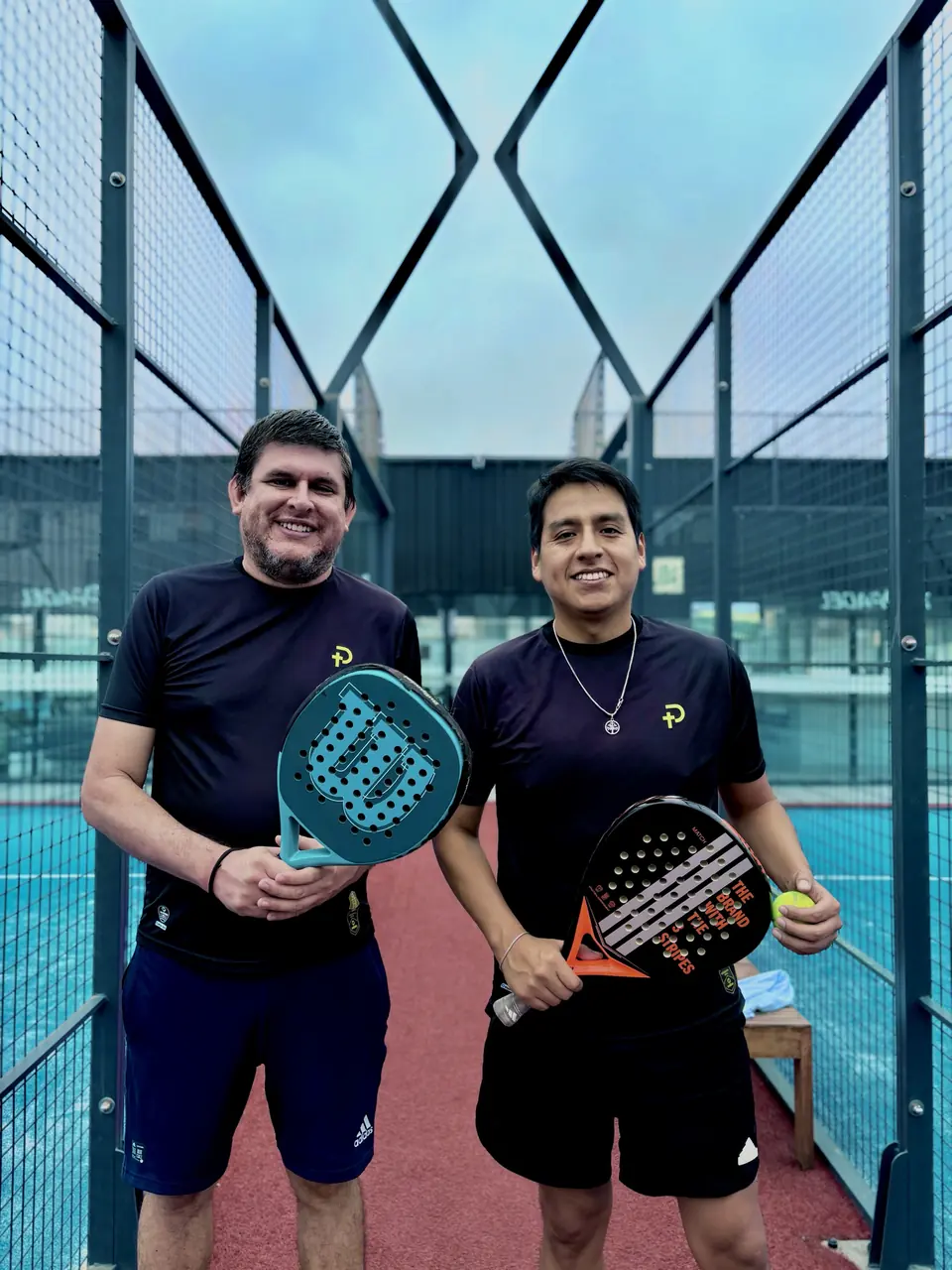Dos jugadores con polos Padelhood mostrando sus raquetas