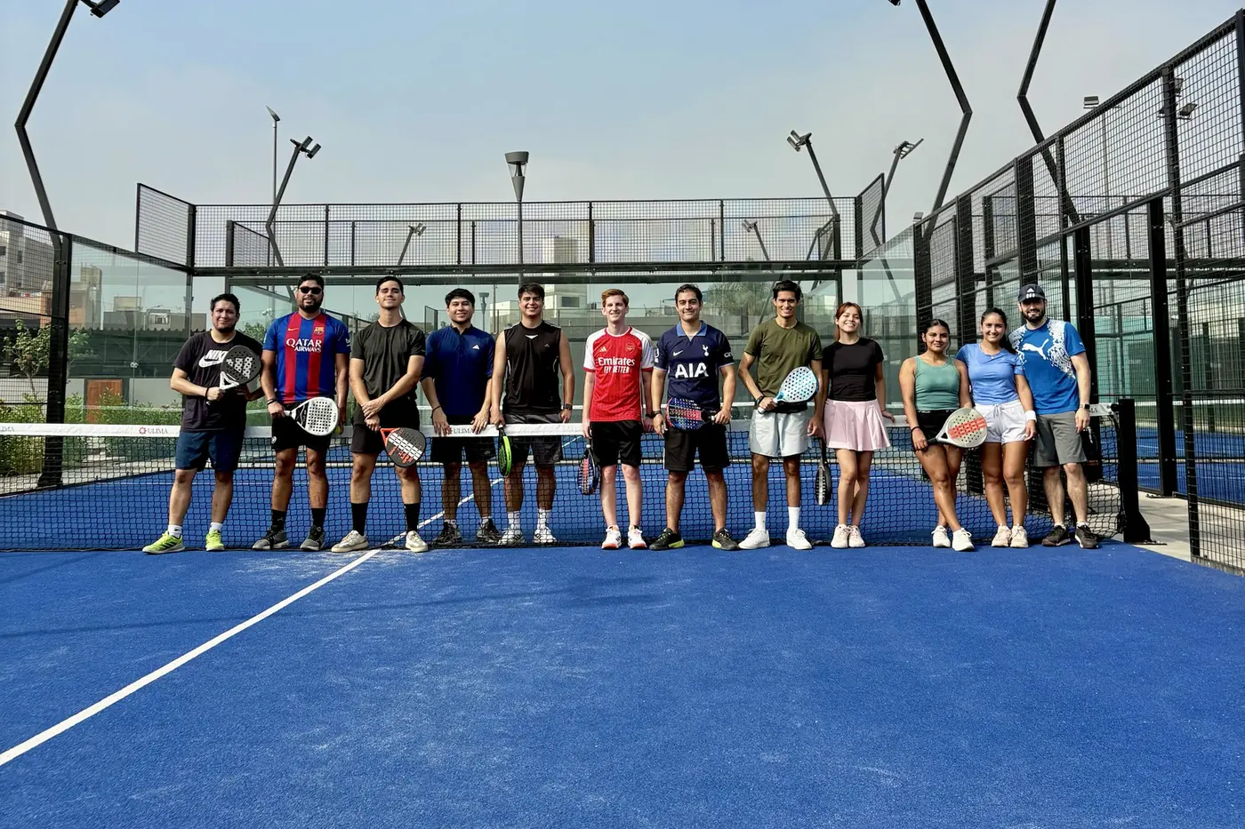 Grupo de jugadores de la comunidad alineados junto a la red de la cancha