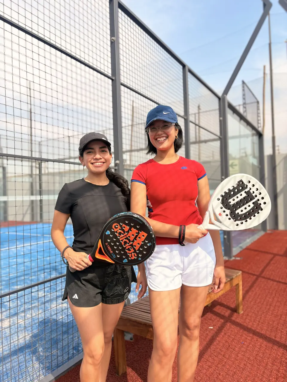 Dos amigas con sus raquetas sonriendo en la cancha