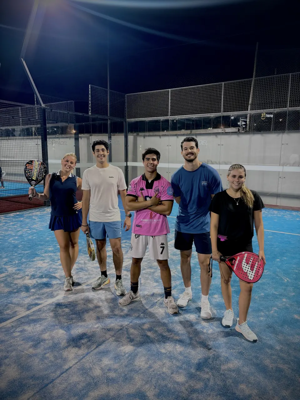 Grupo de cinco amigos posando en una cancha de noche